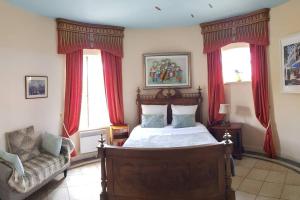 a bedroom with a bed with red curtains and a chair at Beautiful Château with Private Pool near Cahors in Cambayrac