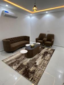 sala de estar con 2 sillas, sofá y alfombra en شقق برج السمو للشقق المفروشة, en Najrán