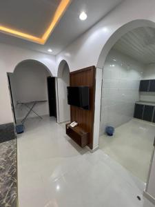 ein Wohnzimmer mit einem TV und ein Zimmer mit weißen Fliesen in der Unterkunft شقق برج السمو للشقق المفروشة in Najran