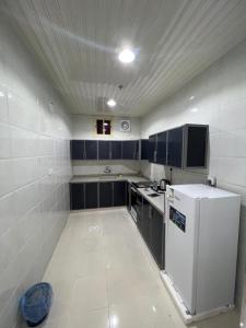una pequeña cocina con nevera blanca y armarios negros en شقق برج السمو للشقق المفروشة en Najrán