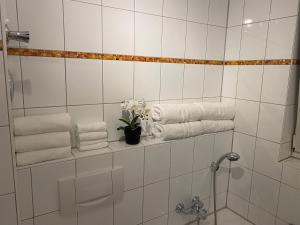 a white tiled bathroom with towels and a vase of flowers at 3 Zimmer Apartment in S-Bahn Nähe, 76 qm, max 5 Pers, 30qm Dachterasse, Garage, Internet 1000 MBit in Gärtringen