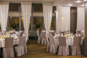 扎莫希奇的住宿－朱比拉酒店，用餐室配有白色的桌子和白色的椅子