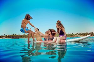 a group of people sitting on a surfboard in the water at Desert Rose Resort in Hurghada