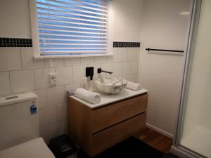 a bathroom with a sink and a toilet and a window at Cheerful 4 Bedroom Holiday Home (Sleeps 7) in Rotorua