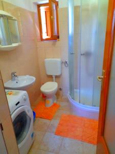 a bathroom with a shower toilet and a washing machine at House Fantazija in Rab