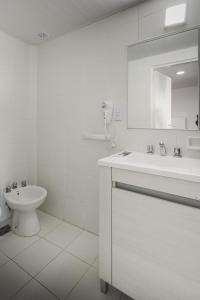 bagno bianco con lavandino e servizi igienici di Hotel Crespo a Crespo