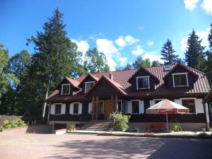 een groot huis met een bruin dak bij Pensjonat Leśny Dworek in Hajnówka