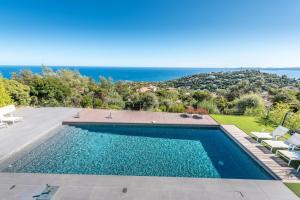 a swimming pool with a view of the ocean at Vue panoramique sur la baie de St Tropez in Les Issambres