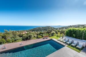 a villa with a swimming pool and a view of the ocean at Vue panoramique sur la baie de St Tropez in Les Issambres