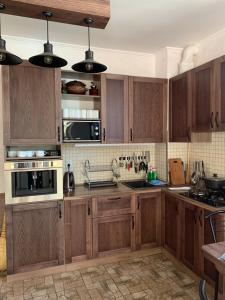 eine Küche mit Holzschränken und Küchengeräten aus Edelstahl in der Unterkunft Family ЛюКс in Kamjanez-Podilskyj