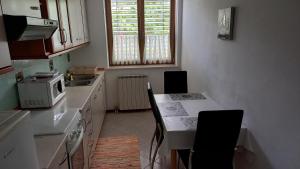 een keuken met een tafel met stoelen en een magnetron bij Apartma Nona Roža in Zgornje Škofije