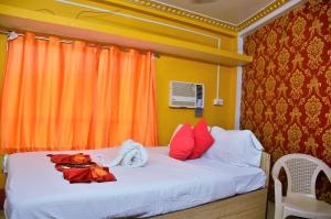 um quarto com uma cama branca e almofadas vermelhas em STAYMAKER Royal Residency em Calcutá