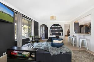 sala de estar con sofá negro y cocina en Home On The Hill- Bowral, en Bowral