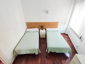 カンブリルスにあるVilla Fortuni Mexico Iのウッドフロアの小さな部屋のベッド2台
