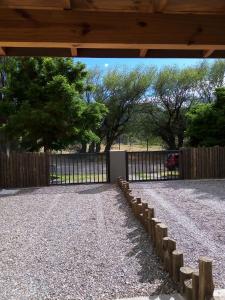 a fence in a yard with a gravel driveway at Duplex Patagonia in Esquel