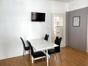 a dining room with a white table and black chairs at Ferienapartment Passauer Wolf im Zentrum in Sankt Pölten