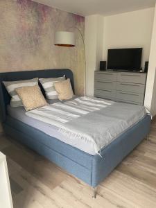ein Schlafzimmer mit einem blauen Bett und einem TV auf einer Kommode in der Unterkunft Erholen Garantiert in Dresden