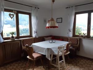 - une salle à manger avec une table, des chaises et des fenêtres dans l'établissement Ferienwohnung Schatzhof, à Jochberg