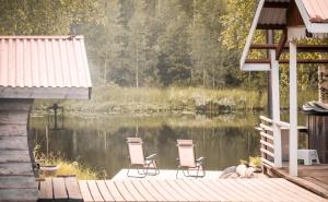 duas cadeiras sentadas numa doca ao lado de um lago em Långforsen Glamping & Lapland Experience 