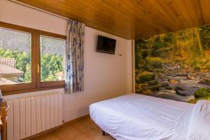ヴィラヨンガ・デ・テルにあるHostal Cal Mestreのベッドルーム1室(ベッド1台付)が備わります。壁には絵画が飾られています。
