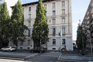 duży biały budynek z samochodami zaparkowanymi przed nim w obiekcie YouHosty - Pavia 7 w Mediolanie