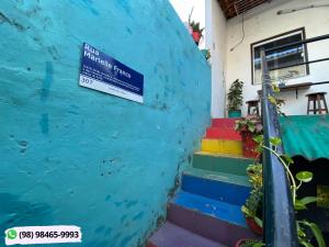 un panneau sur le côté d'une maison avec marches colorées dans l'établissement Guarnicê Hostel, à São Luís