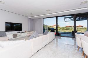 a living room with white furniture and large windows at 10-11 Ocean’s Edge, Zimbali – 8 Bedroom in Ballito