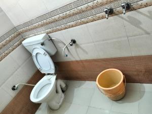 ein Badezimmer mit einem WC und einem Eimer in der Unterkunft Hotel Anta Palace & Spicy Restaurant By WB Inn in Bharatpur