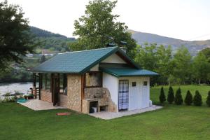 una pequeña casa con chimenea de piedra en un patio en Idyllic river front holiday houses - Tišine, en Goražde