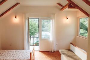 um quarto com uma cama e uma grande janela em Idyllic river front holiday houses - Tišine em Goražde