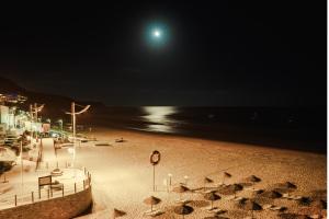 uma praia à noite com lua cheia em Casa Praia Mar em Salema