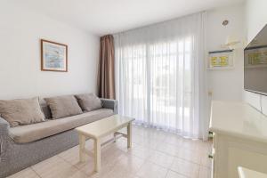 een woonkamer met een bank en een tafel bij Flatguest Alisios Playa 4 in Corralejo