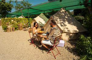 a man and woman sitting at a table in front of a tent at Kampaoh Los Escullos in Almería