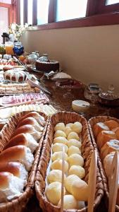 una mesa cubierta con cestas de pan y bollería en Pousada Condado Brasileiro, en Campos do Jordão
