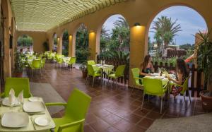 Dos mujeres sentadas en mesas en un restaurante con sillas verdes en Kampaoh Los Escullos, en Almería