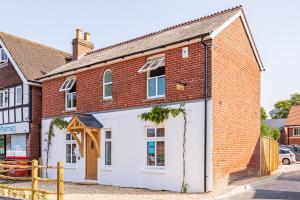 an old brick house with a white garage at Westview Cottage bikes/chef/hot tub in Sway