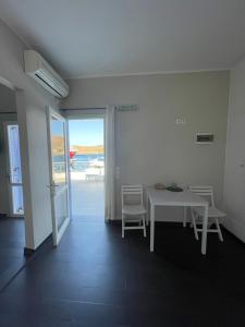 AEGEAN VIEW SEASIDE ROOMS AND STUDIOS KEA في Korissia: طاولة بيضاء وكراسي في غرفة مطلة على المحيط