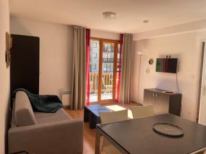 a living room with a couch and a table at Appt 4 a 6 pers aux pieds des pistes Les terrasses du soleil d or résidence avec piscine in Les Orres