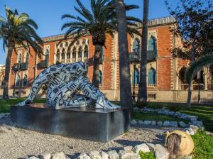 une statue devant un bâtiment planté de palmiers dans l'établissement La Casa di Nausicaa : il piacere dell'ospitalità, à Reggio de Calabre