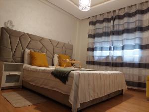 a bedroom with a bed with yellow pillows and a window at Studio Superbe Parc Mohammedia in Mohammedia