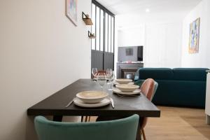 a dining room with a table with plates and wine glasses at L'Arty - Très joli studio moderne place Valmy in Lyon