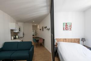 a bedroom with a bed and a couch and a kitchen at L'Arty - Très joli studio moderne place Valmy in Lyon