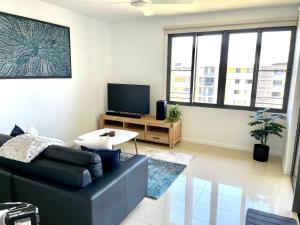 a living room with a couch and a tv at Serenity Zealandia - Luxury 1brm unit at Darwin Waterfront in Darwin