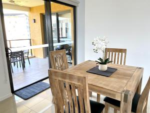 een eetkamer met een houten tafel en stoelen bij Serenity Zealandia - Luxury 1brm unit at Darwin Waterfront in Darwin