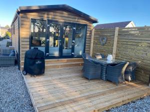 eine Holzterrasse mit einem Tisch und Stühlen darauf in der Unterkunft Ferienhaus Feldblick in Fehmarn