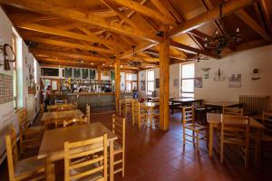 un restaurante con mesas y sillas de madera y un bar en Kampaoh Sierra de Urbasa, en Bacáicoa