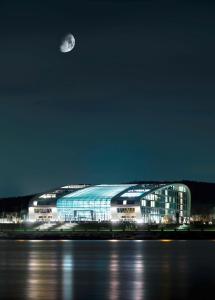 a large building at night with the moon in the sky at Kameha Grand Bonn in Bonn