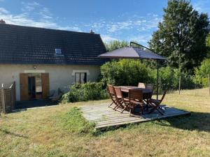 a table and chairs with an umbrella in a yard at Le moulin Bertrand in Martigny-Courpierre