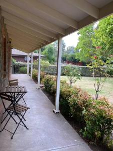 eine Veranda mit zwei Bänken und einem Tisch im Garten in der Unterkunft Cook's Cottage in Balhannah in Balhannah