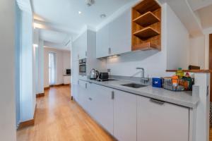 a kitchen with white cabinets and a wooden floor at Studio - Tower Hill - City Centre by Prime London Stays N-5 in London